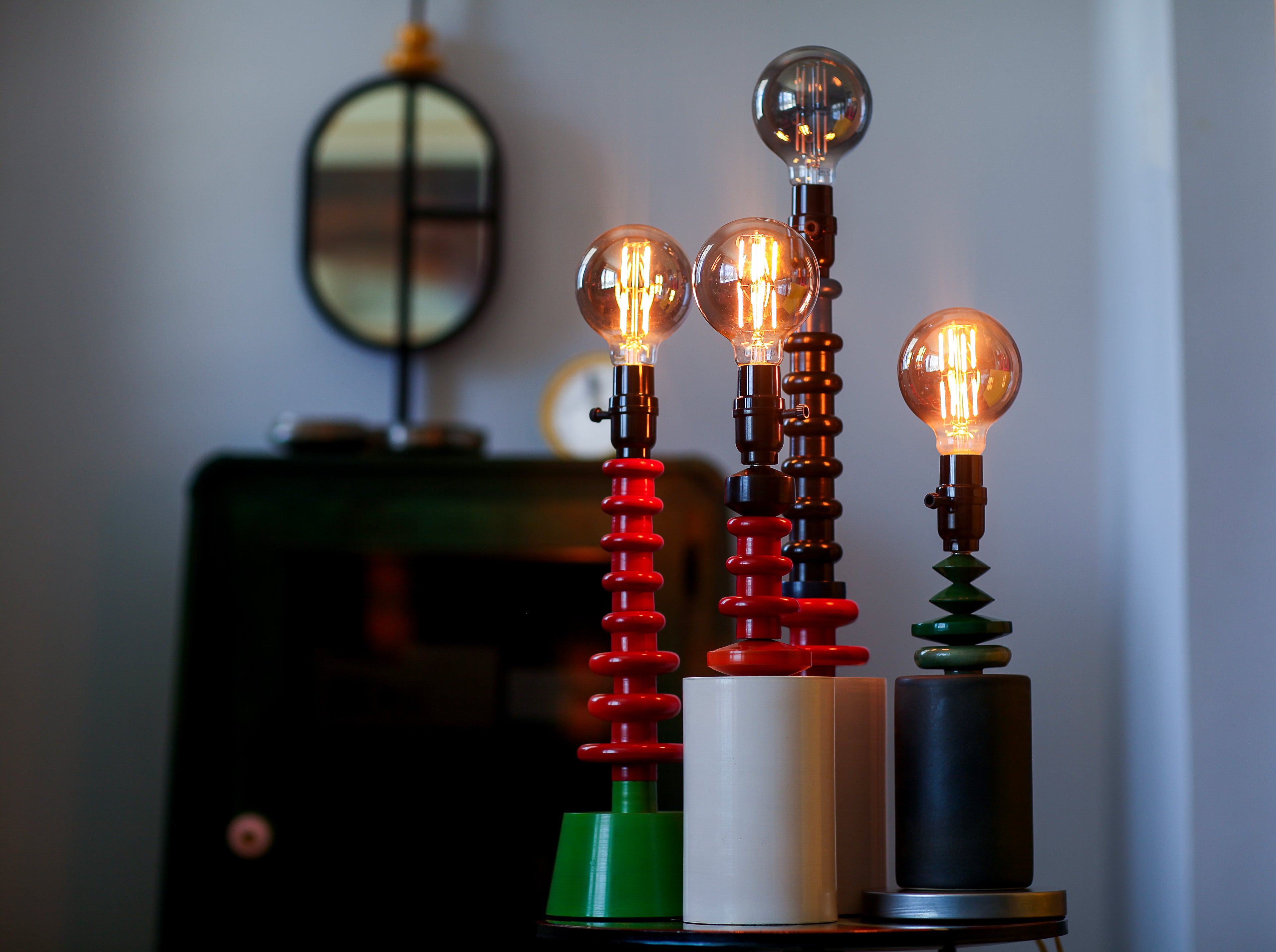 Three unique lamps with glowing bulbs on a blurred background.