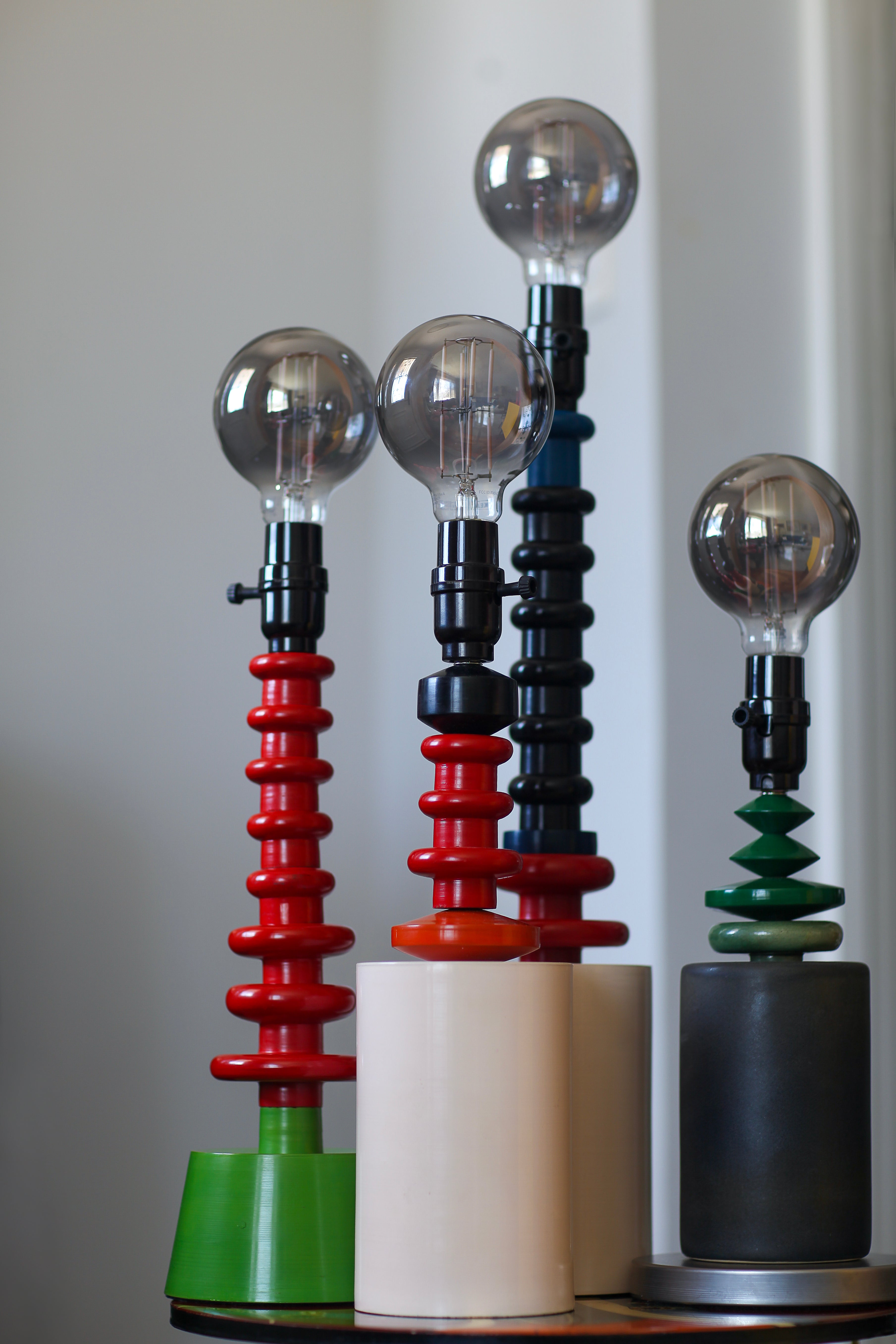 Colorful glass orb lamps with metallic bases on a neutral background